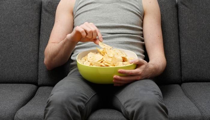 man eating chips on the sofa